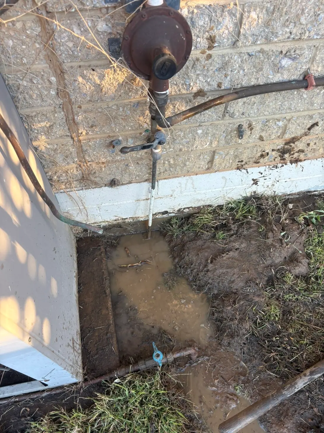 Gas meter and pipework exposed at the base of a wall