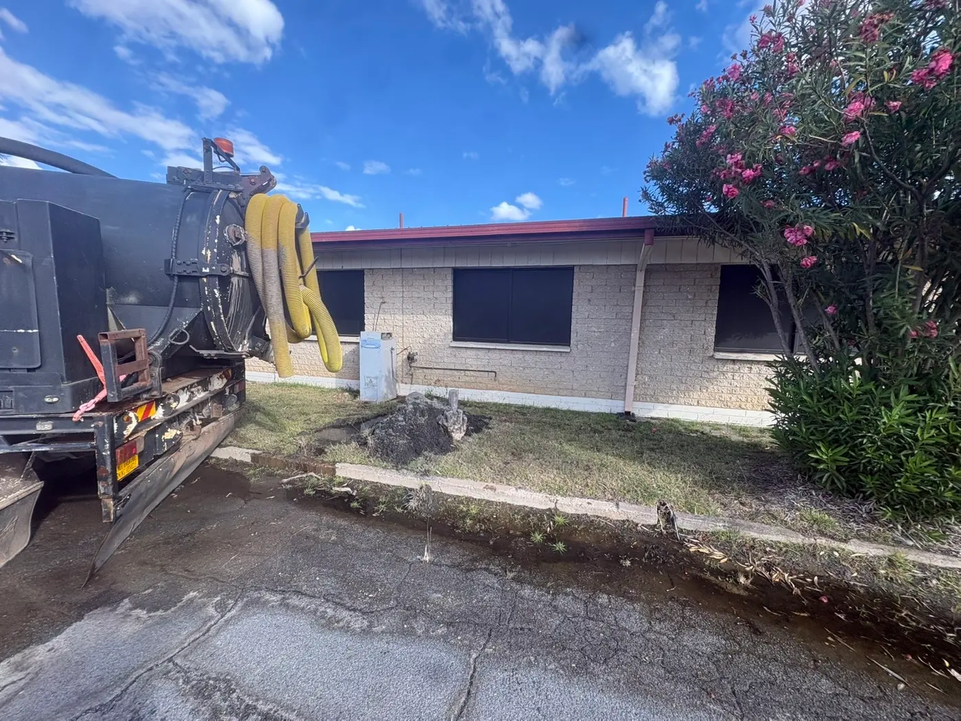 Vacuum truck hydro excavating a hole beside a building