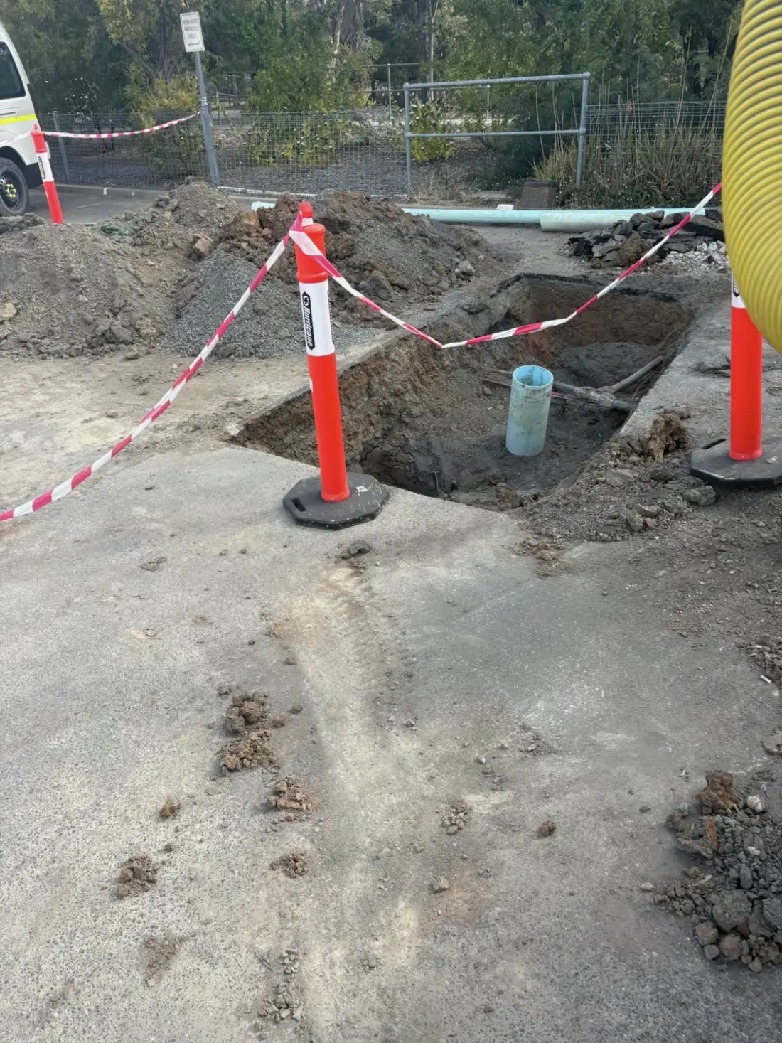 Hydro excavated pit with exposed service pipe and safety barriers